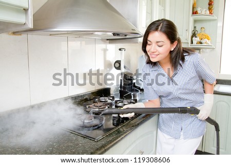 Modern kitchen - happy woman steam cleaning