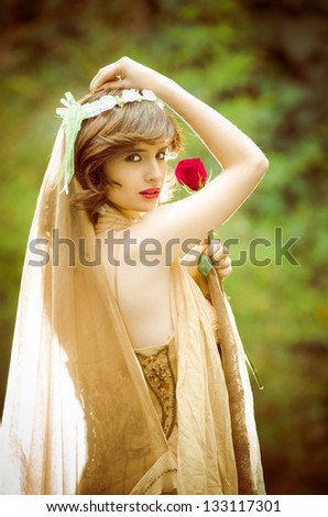 Portrait of romantic woman in fairy forest with a rose