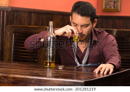 man in suit drinking alcohol shot with empty bottle