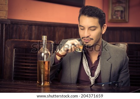 latin american man in suit drinking alcohol shot getting drunk