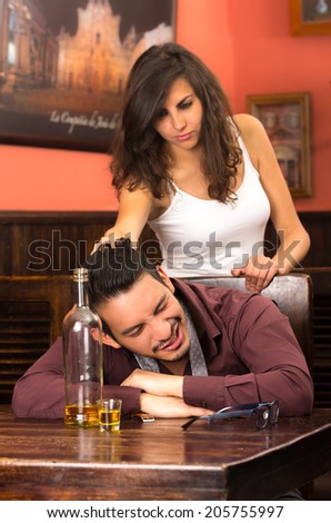 drunk young man sleeping and angry girlfriend in a bar pulling his hair