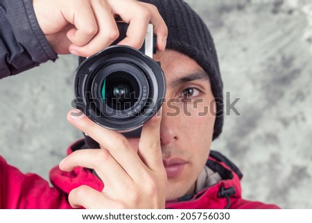 closeup of young man in winter clothes taking photos front view over grey background