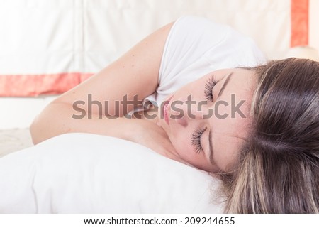 Attractive young woman sleeping in bed onher side