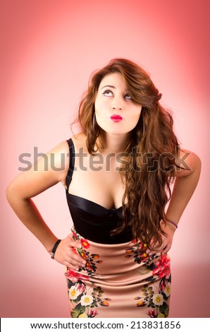 Sexy retro young woman sending a kiss with hands on hips over red background
