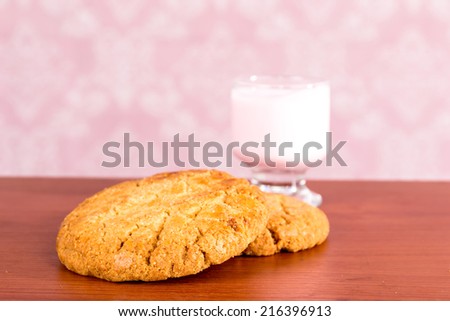 Two big homemade cookies and a glass of strawberry yogurt on wooden kitchentop selective focus