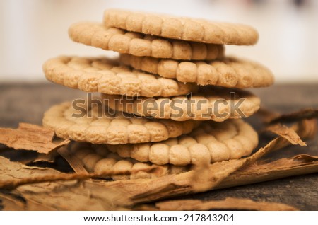 pile of delicious vanilla cookies surrounded by cinnamon sticks on wooden table