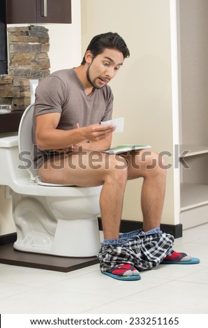 worried man sitting on the toilet with last sheet of toilet paper