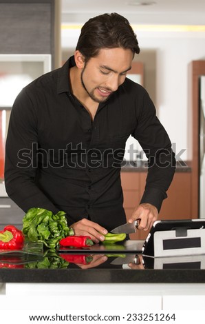 handsome young happymodern man cooking healthy recipe while using tablet