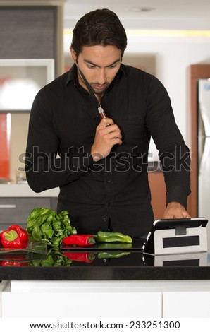 handsome young modern man cooking healthy recipe while using tablet