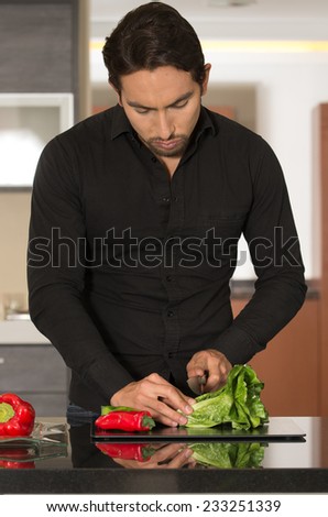 handsome young man cooking cutting vegetables in modern kitchen