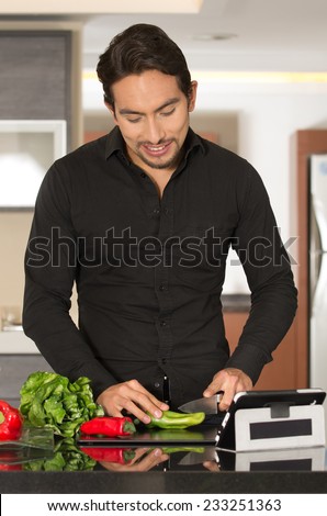 handsome young relaxedmodern man cooking healthy recipe while using tablet