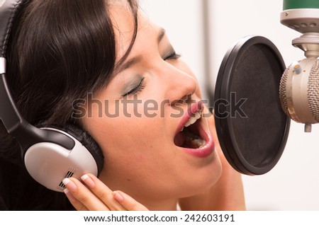beautiful young brunette girl singing in music studio