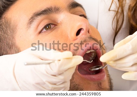 closeup portrait of young handsome man at the dentist with mouth open