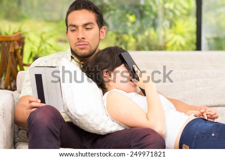 young attractive happy couple relaxing in the sofa using tablet