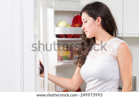 young beautiful brunette woman searching for food in the fridge
