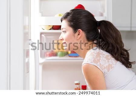 young beautiful brunette woman searching for food in the fridge