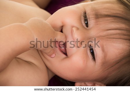 portrait of adorable brunette baby girl with finger in mouth isolated on white