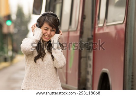 portrait of woman walking on the city street wearing headphones concept of noise pollution