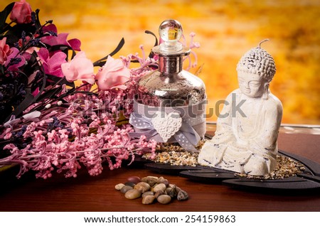 glass bottle and buddha statue with pink flowers spa concept