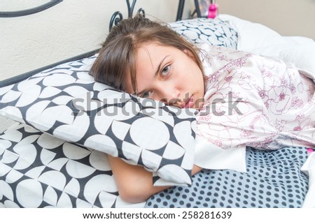 cute sleepy drowsy young girl waking up in bed hugging her pillow