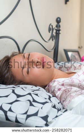 cute sleepy young girl unwilling to get up from bed