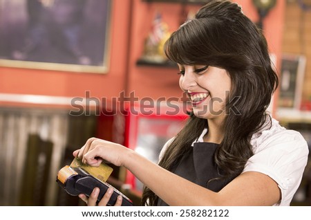beautiful young friendly waitress swiping credit card