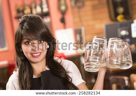 happy cute waitress holding empty beer glasses in bar