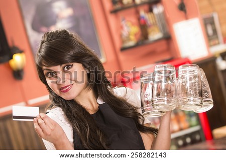 happy cute waitress holding empty beer glasses and credit card in bar