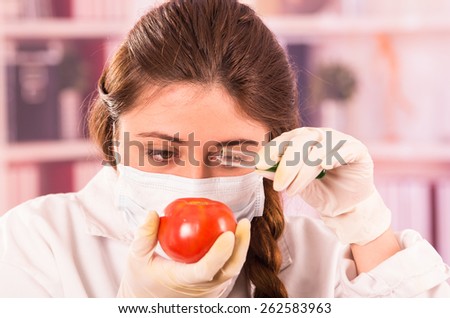 young beautiful woman biologist experimenting with a tomato in a lab