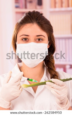 young female biologist wearing mask experimenting with leaf in lab