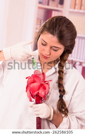 beautiful female biologist botanist experimenting with red flower in the lab