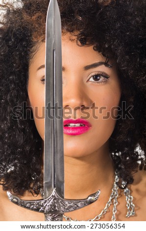 close up shot of beautiful exotic young latin woman holding a dagger sword in front of her face isolated on white