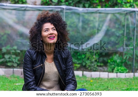 exotic beautiful young girl with dark curly hair relaxing in the garden