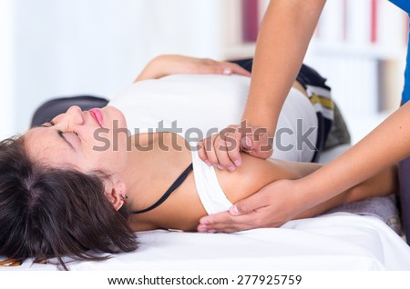 young woman in pain lying while getting a massage from specialist concept of physiotherapy