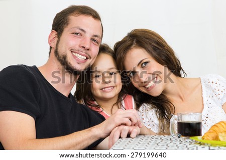 Sweet small family of three with little girl smiling at camera, close up