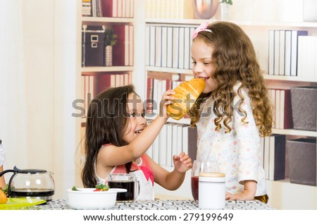 Cute little preschooler girl feeding bread to her sister