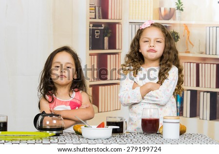 Two young preschooler girls looking upset refusing to eat their meal