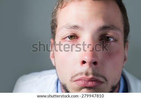 Closeup portrait of sad young doctor crying over gray background