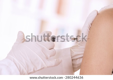 closeup of doctor\'s hand with injection holding patients shoulder isolated on white