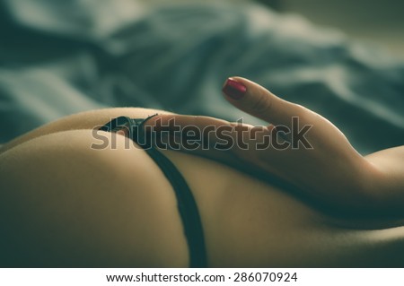 closeup of sexy womans back wearing thong with hand reaching to string