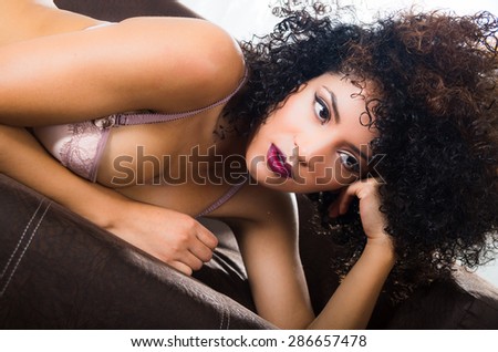 closeup of girl posing sensually in sofa wearing lingerie supporting her head with left arm
