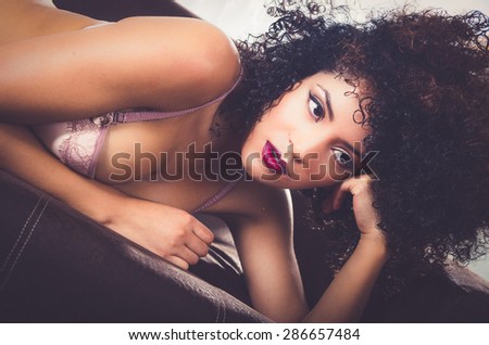 closeup of girl posing sensually in sofa wearing lingerie supporting her head with left arm