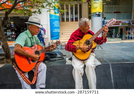 ARMENIA, COLOMBIA - FEBRUARY 23, 2015: two unidentify indigenous men playing guitar in the commercial street of Armenia