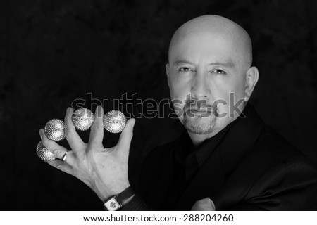 Magician man posing with five balls between fingers black and white edition