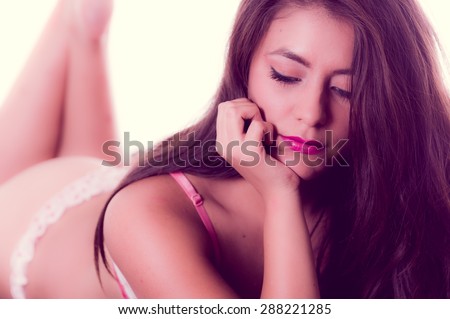 Hispanic model posing lying down with hand supporting head and looking down