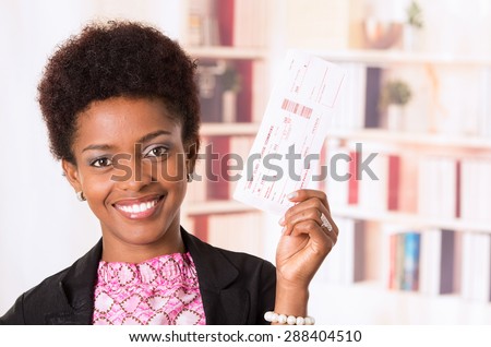 Black office woman holding ticket next to her head and smiling concept transport airplane airline bus train traveling airport counter depart flight