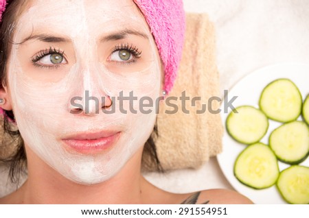 Closeup woman from above angle with white cream covering face looking to the side of camera