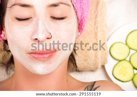 Closeup woman from above angle with white cream covering face and eyes closed