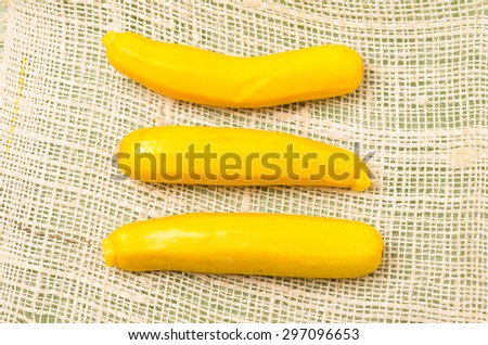 three fresh organic yellow zucchinis on hemp cloth.