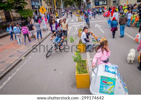 BOGOTA, COLOMBIA - FEBRUARY 9, 2015: Unidentified hispanic pedestrians, cyclists, dogs and food vendors moving through city street Candelaria area Bogota